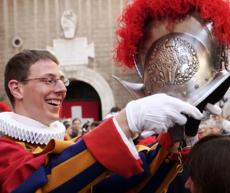 An unidentified Swiss Guard admires his metal helmet at the Vatican.
