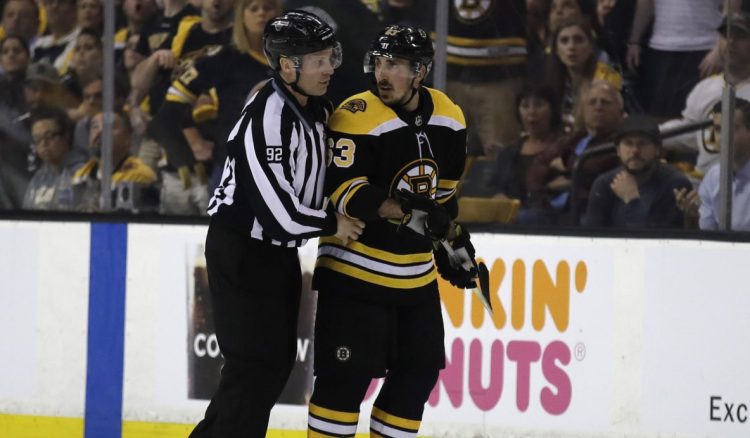Boston Bruins left wing Brad Marchand (63) is escorted to the penalty box during a game against the Tampa Bay Lightning in Boston this month. The NHL has told Marchand to stop licking opponents or the Boston Bruins forward will face punishment.