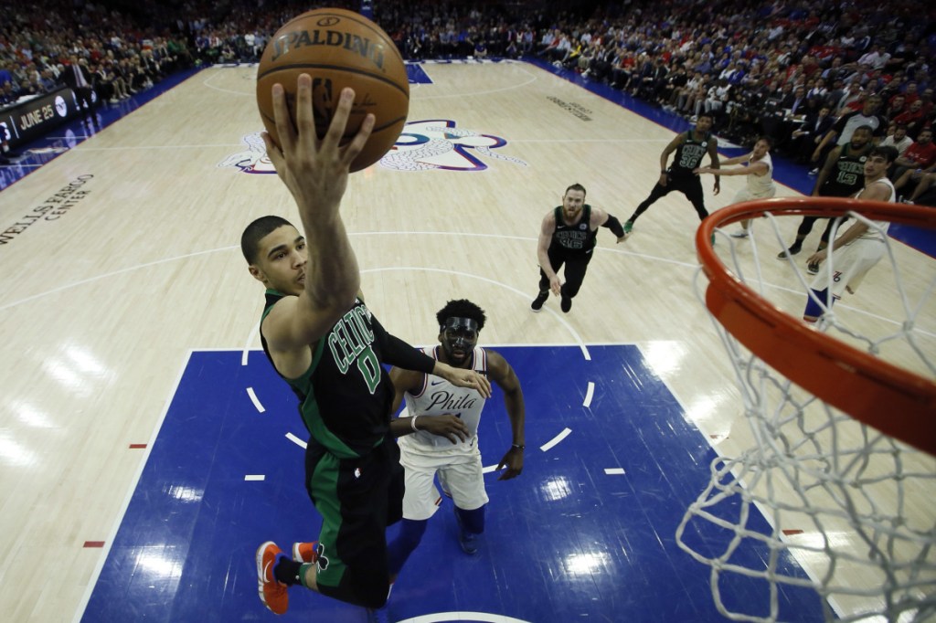 Boston's Jayson Tatum, left, gets past Philadelphia's Joel Embiid and goes strong to the basket.