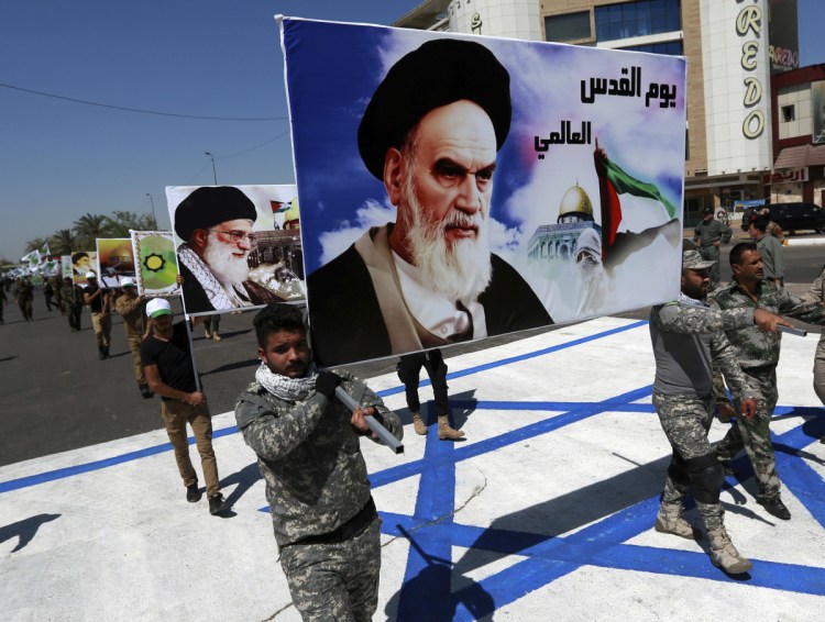 Supporters of Iraqi Hezbollah brigades march on a representation of an Israeli flag with a portrait of late Iranian leader Ayatollah Khomeini and Iran's supreme leader Ayatollah Ali Khamenei, in Baghdad in 2017.