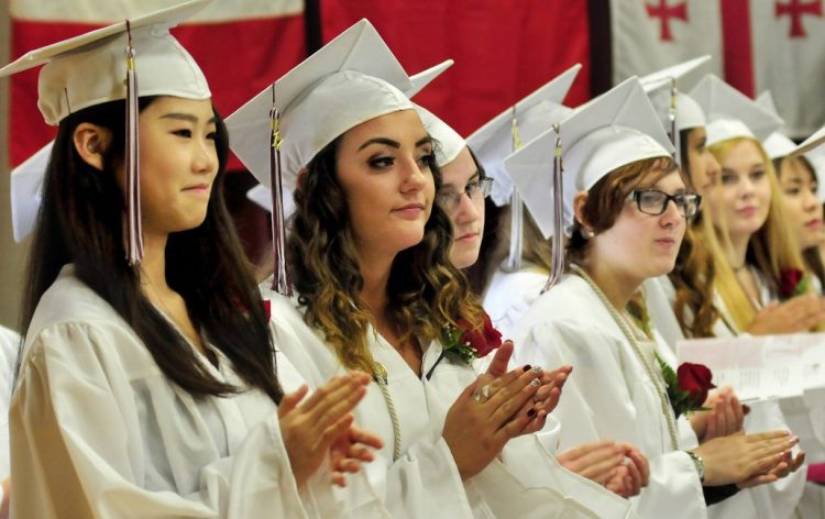 Graduating seniors clap for a classmate during commencement at Maine Central Institute last June 4. The Pittsfield secondary school is reducing its staff because of declining international enrollment.