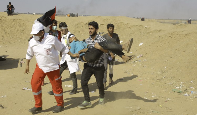 Palestinian medics and protesters evacuate a wounded youth east of Khan Younis in the Gaza Strip on Tuesday. Israel faced a growing backlash Tuesday and new charges of using excessive force, a day after Israeli troops firing from across a border fence killed at least 60 Palestinians and wounded more than 2,700 at a mass protest in Gaza.