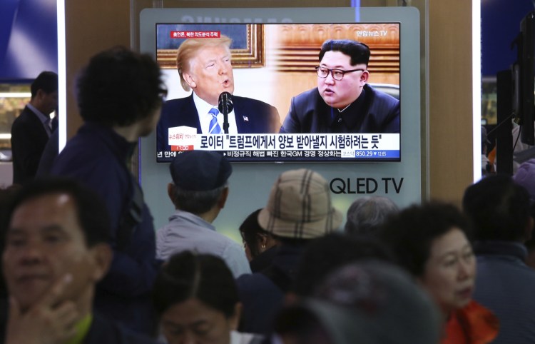 People watch a TV showing split-screen images of U.S. President Trump and North Korean leader Kim Jong Un during a news program at the Seoul Railway Station in Seoul, South Korea, on Wednesday. North Korea on Wednesday threatened to scrap a historic summit next month between Kim and Trump, saying it has no interest in a "one-sided" affair meant to pressure Pyongyang to abandon its nuclear weapons. The signs read: " Trying to test Trump."