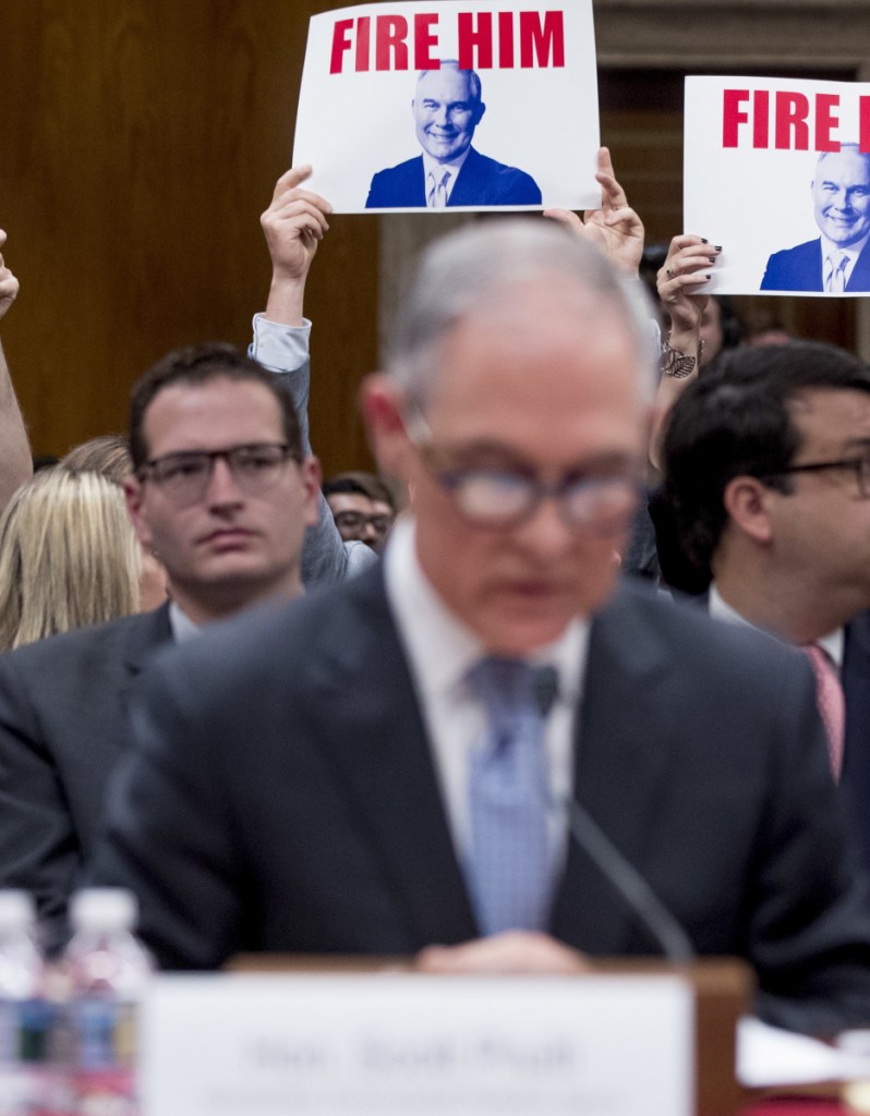 Members of the audience hold signs reading "Fire Him" as EPA Administrator Scott Pruitt, center, testifies Wednesday before a Senate appropriations subcommittee.