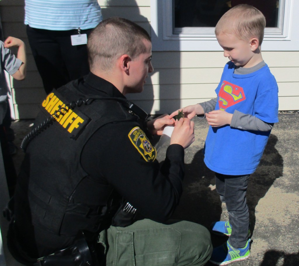 York County Sheriff's Deputy Travis Belleard interacts with youths in Sanford. The deputy awarded them police badges and let them sit inside a cruiser as part of an exchange between the sheriff's department and the Waban Fraser-Ford Child Development Center in Sanford.
