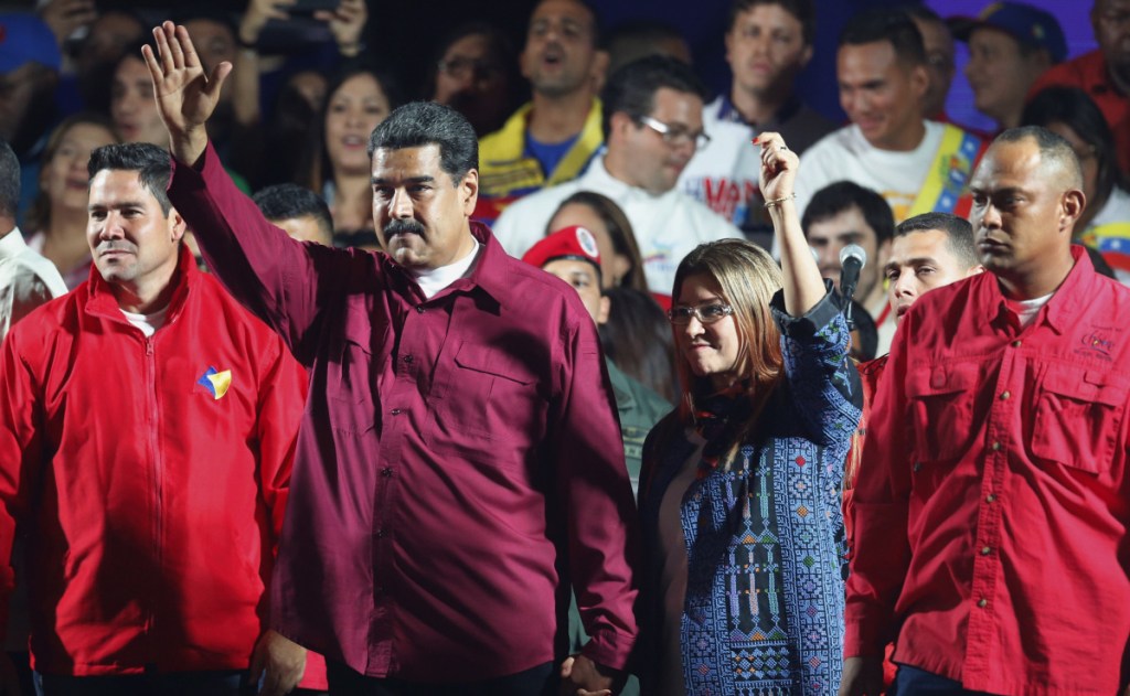 Venezuela's President Nicolas Maduro and his wife Cilia Flores wave to supporters after the National Electoral Council announced that with almost 93 percent of polling stations reporting, Maduro won nearly 68 percent of the votes in Sunday's election.