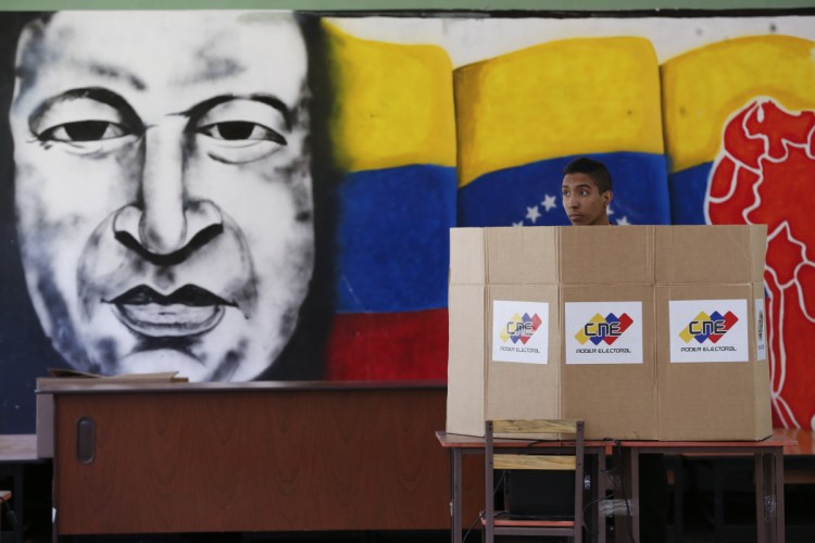 A voter stands in front of a mural of late Venezuelan President Hugo Chavez during elections in Caracas on Sunday. Nicolas Maduro secured his second six-year term as president in a vote marred by an opposition boycott.