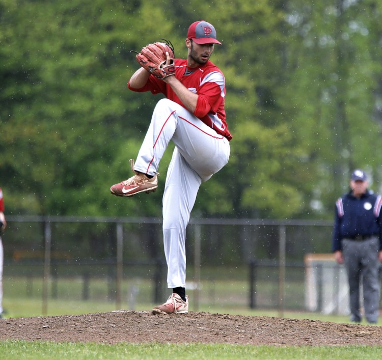 As a persistent rain falls, South Portland pitcher Zach Johnson delivers a pitch against Thornton Academy on Tuesday in Saco. Johnson and the Red Riots beat the Trojans, 9-6.