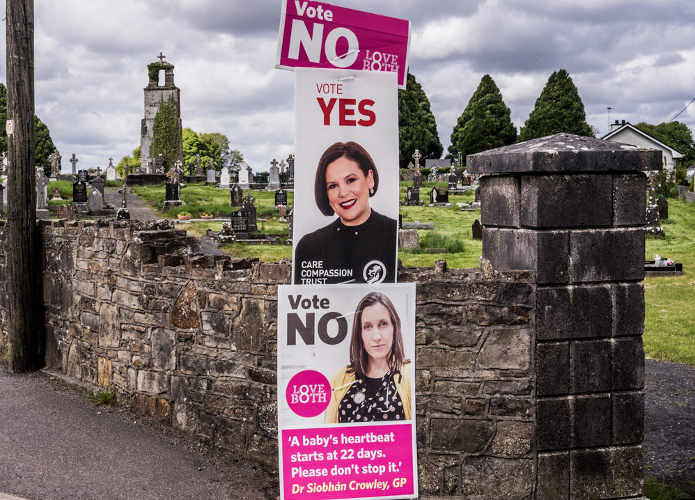 Signs for repealing and keeping Ireland's abortion ban can be seen outside a cemetery in Castlerea, Ireland.