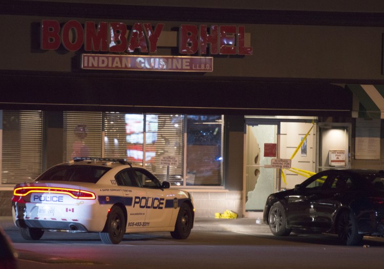 Police stand outside the Bombay Bhel restaurant in Mississauga, Canada, on Friday.    