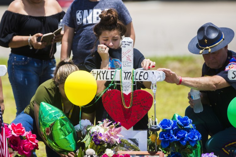 A young woman cries by a memorial to Santa Fe (Texas) High School shooting victim Aaron Kyle McLeod. Making schools "more like prisons" won't prevent more such tragedies, a reader says.