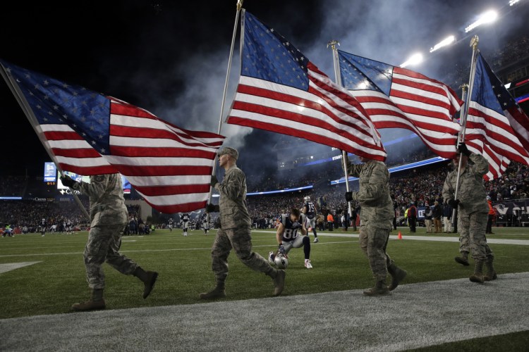 New England Patriots wide receiver Danny Amendola kneels as U.S. service members carry American flags on the field before an NFL divisional playoff game on Jan. 13. The league's support for patriotism doesn't extend to embracing a player's right to stand up for his principles.