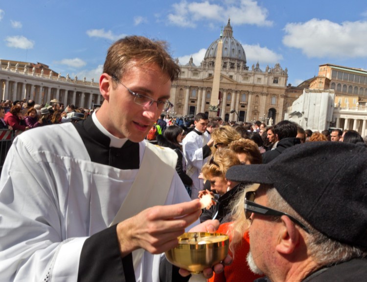 A priest delivers communion to the faithful in St. Peter's Square during the inauguration Mass for Pope Francis at the Vatican in 2013.