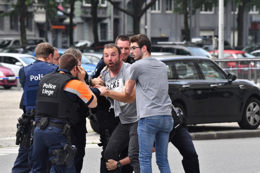 Police try to calm a man at the scene of the shooting in Liege, Belgium.