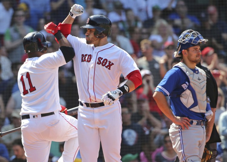 J.D. Martinez celebrates his two-run home run with Red Sox teammate Rafael Devers, left, with Toronto catcher Luke Maile at right, in the sixth inning of Wednesday's game at Fenway Park in Boston.