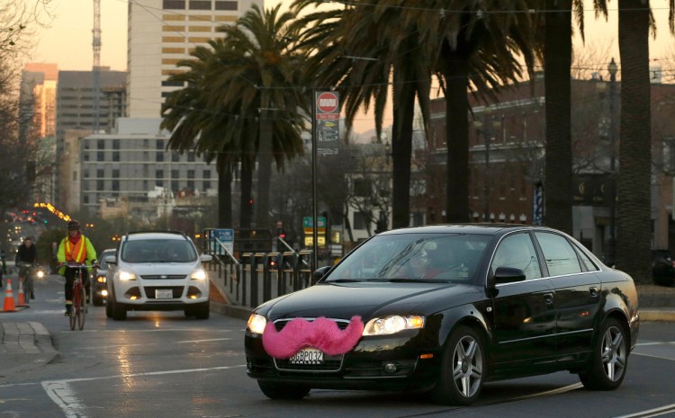 A Lyft car sports the company's unique pink mustache on Market Street in San Francisco in 2013. The mustache logo was replaced in 2016 as the company evolved and spread around the world. But while Lyft – as well as Uber – continue to expand, some of their drivers complain that compensation has been lackluster.