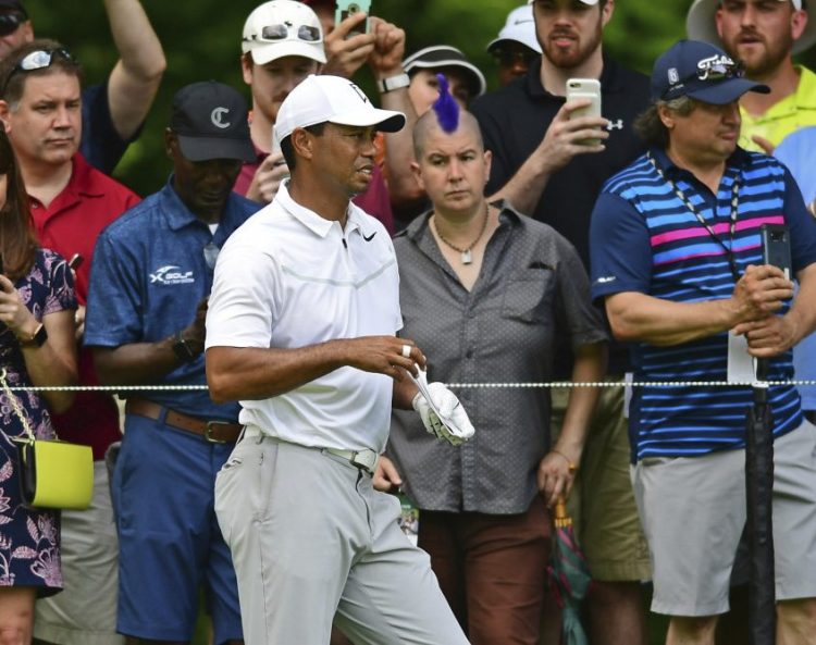 Tiger Woods examines the fairway while spectators take pictures on the ninth hole Thursday during the first round of the Memorial golf tournament in Dublin, Ohio.