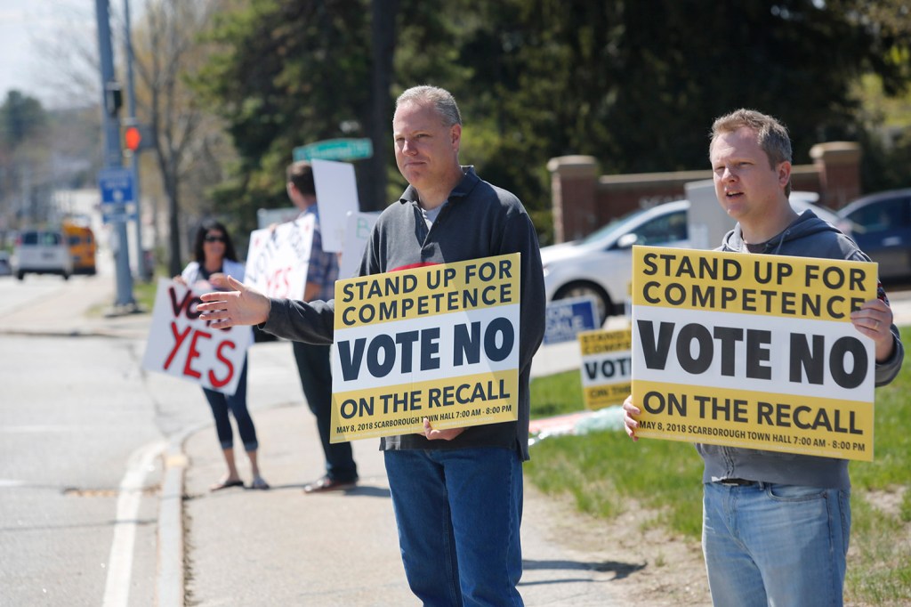 Rodger Kueck, left, and Brent Crossman hold up "No" signs to passing traffic on Route 1 as Racquel Undlin and Matt Sither hold "Yes" signs. The special election on the recall of three school board members clearly divided the town.
