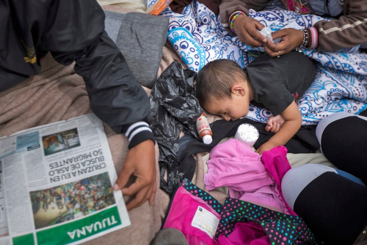 A 2-year-old child from Honduras gets treatment for an ear infection after sleeping in the open in front of the El Chaparral port of entry, in Tijuana, Mexico, Monday. About 200 people in a caravan of Central American asylum seekers waited on the Mexican border with San Diego for a second straight day on Monday to turn themselves in to U.S. border inspectors, who said the nation's busiest crossing facility did not have enough space to accommodate them.