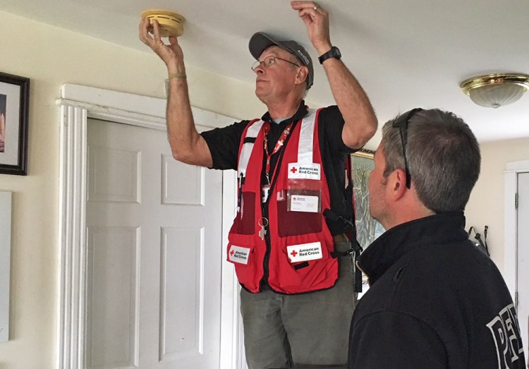 Volunteer John Cordts checks the condition of a homeowner's smoke alarm, while Brandon Farley watches. Farley is a firefighter and paramedic and vice president of Local 740 of the Portland Professional Firefighters.