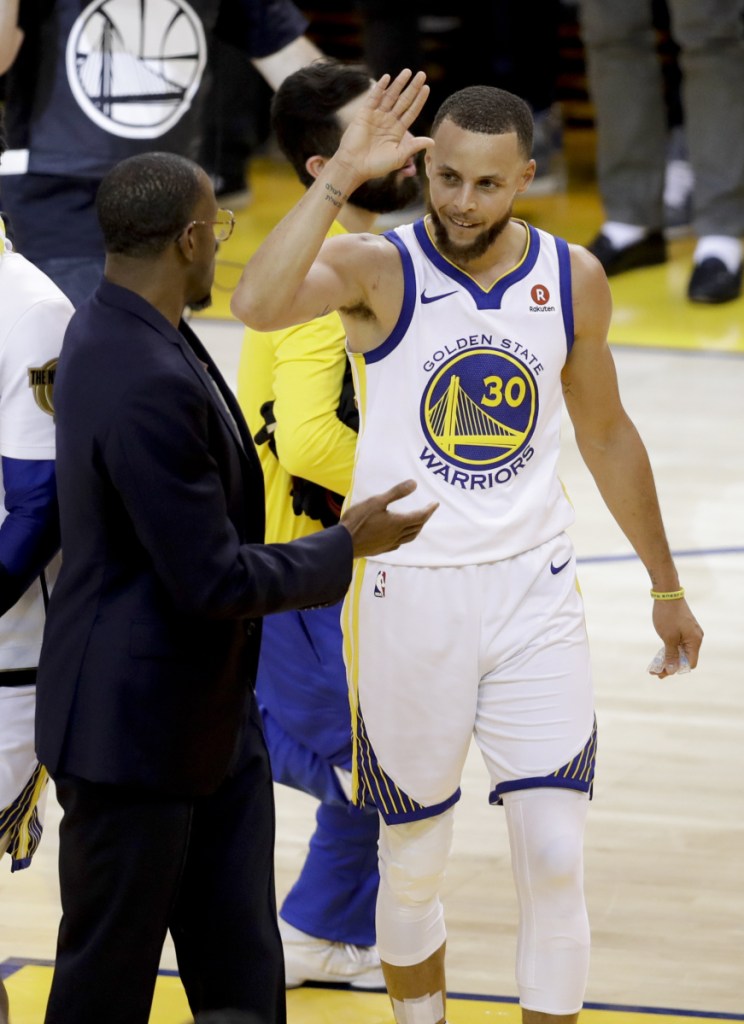 The Warriors' Stephen Curry is congratulated by injured forward Andre Iguodala, in suit, and teammates after scoring in the first half of Thursday night's game.