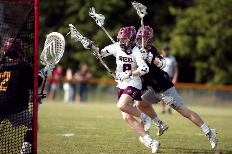 Andrew Lawrence of Greely is tripped up by Cape Elizabeth defenders Brendan Goss and Sam Loring before unloading a shot on goalkeeper Jack Dresser during their boys' lacrosse game Friday. Cape Elizabeth held on for an 11-9 victory.