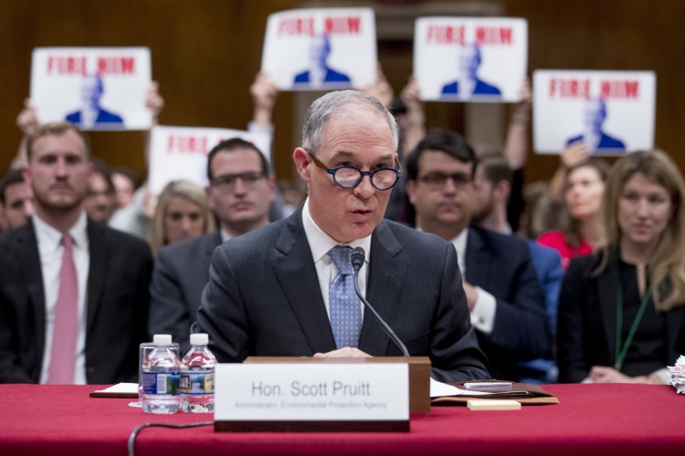 Audience members hold up signs that read "Fire Him" as Environmental Protection Agency Administrator Scott Pruitt testifies before a Senate Appropriations subcommittee in May.