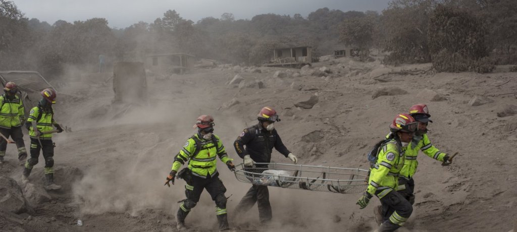 Rescue workers run for cover as the Volcan de Fuego, or "Volcano of Fire," blows more clouds of ash in the El Rodeo hamlet of Escuintla, Guatemala, Tuesday. Officials fear the number of dead was sure to climb.