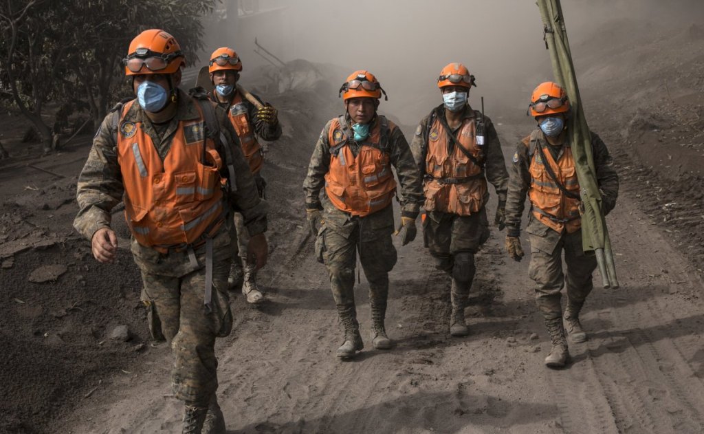 Rescue workers walk near the Volcan de Fuego in El Rodeo, Guatemala, Wednesday. Nearly 200 people are still missing.