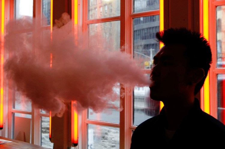 A customer exhales vapor from an e-cigarette at a store in New York. Many e-cigarette and vaporizer sellers have started offering scholarships as a way to get brands listed on university websites and to get students to write essays about vaping.