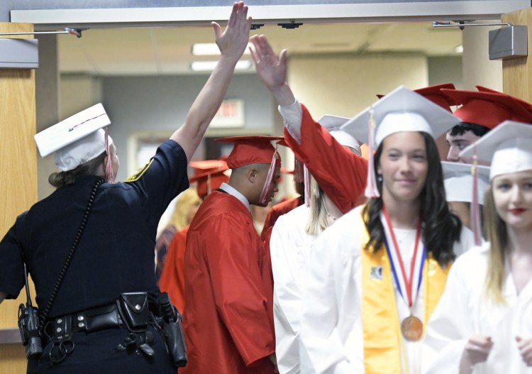 Augusta police Officer Carly Wiggin high-fives graduates of Cony High School on Sunday before graduation ceremonies at the Augusta Civic Center.
