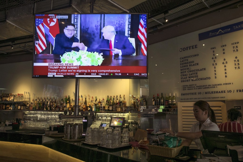 A screen displays a news broadcast of President Trump and North Korean leader Kim Jong Un shaking hands at a document-signing event, in a restaurant in Singapore on Tuesday.