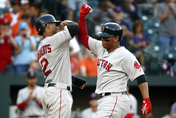 Boston's Xander Bogaerts, left, greets Rafael Devers at home plate after scoring on Devers' two-run home run during the second inning of Tuesday's game against the Orioles in Baltimore.