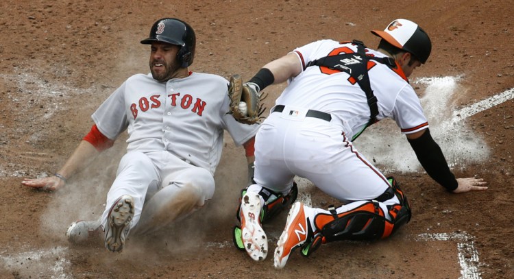 Boston's J.D. Martinez slides past Orioles catcher Austin Wynns for a run on Eduardo Nunez's RBI single in the fifth inning Wednesday in Baltimore. The Red Sox finished their sweep with a 5-1 win.