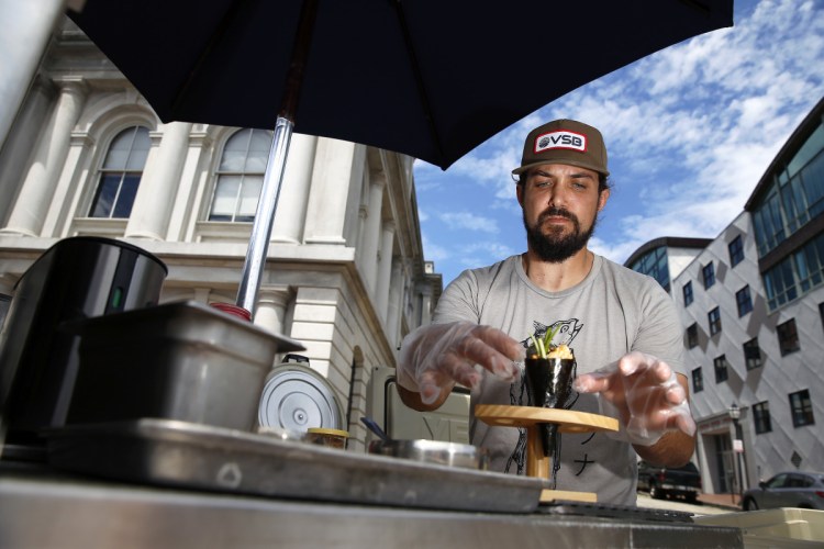 Jordan Rubin, owner of Mr. Tuna Mobile Sushi Bar, prepares a spicy scallop and crab handroll at the corner of Commercial and Custom House streets.