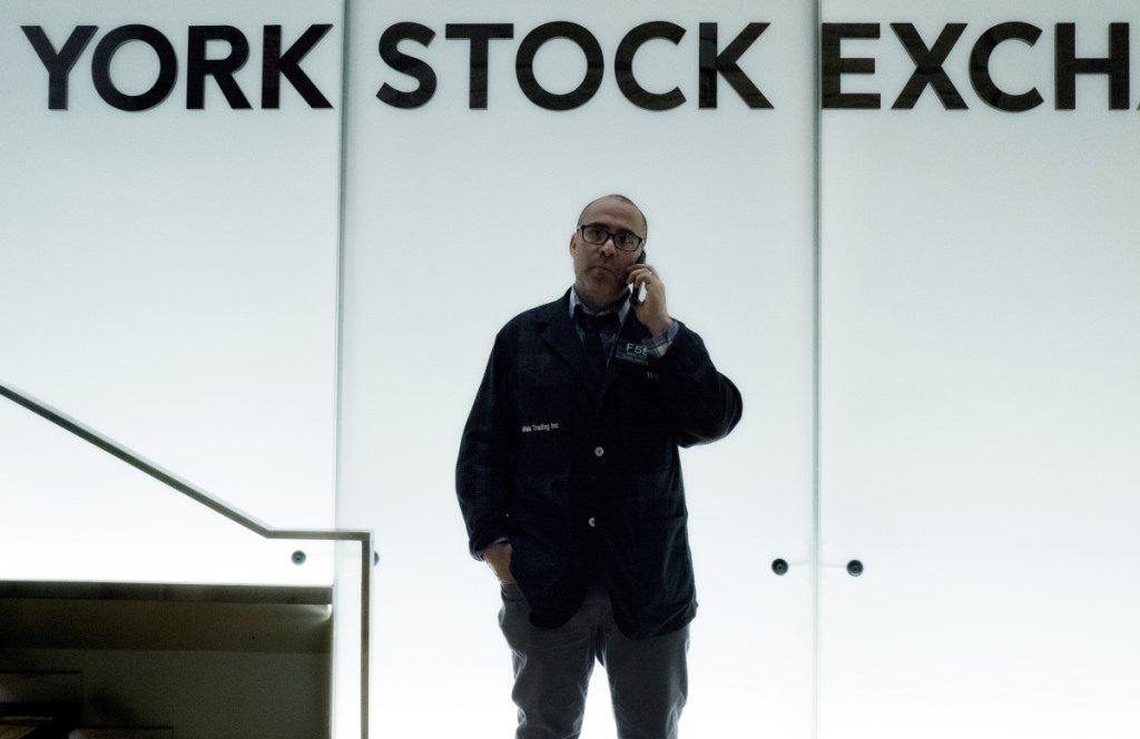 A trader talks on his phone before the start of trading Monday at the New York Stock Exchange.