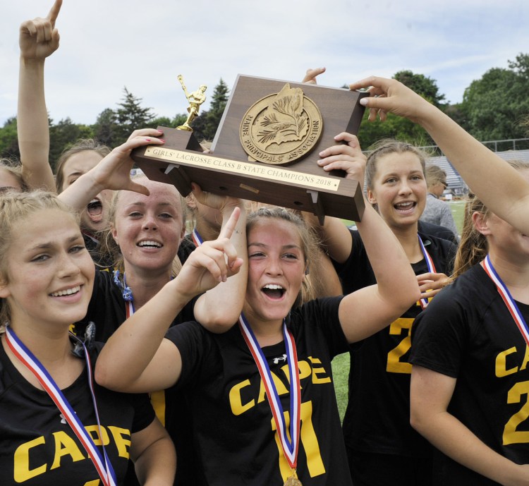 Cape Elizabeth's Cloe Chapin holds the Class B state championship plaque and celebrates with teammates after they won the state title Saturday in Portland.