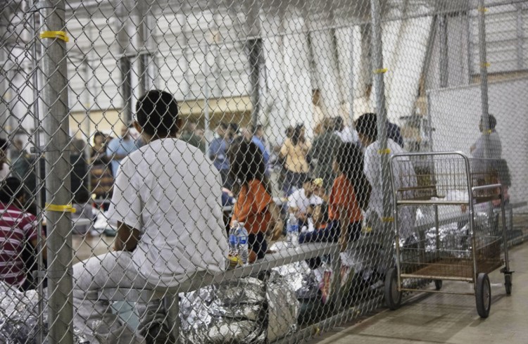 People who have been taken into custody, related to cases of illegal entry into the United States, sit in one of the cages at a facility in McAllen, Texas, on Sunday. Several states are now recalling or refusing to send National Guard troops to the border because of the Trump administration policy of separating children and parents.