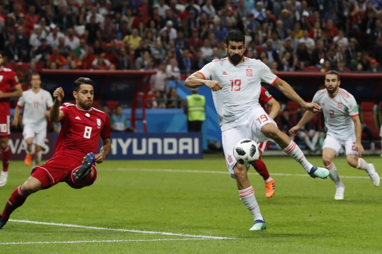 Spain's Diego Costa, right, shoots as Iran's Morteza Pouraliganji tries to block during the group B match between Iran and Spain at the World Cup on Wednesday. Spain won, 1-0.