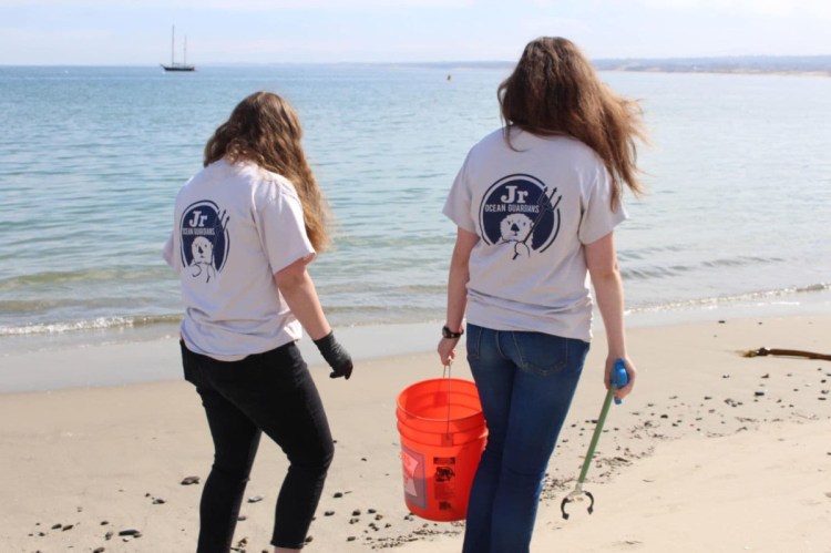 Shelby O'Neil, left, and a friend clean up trash from  a beach in Monterrey, Calif. in 2017.