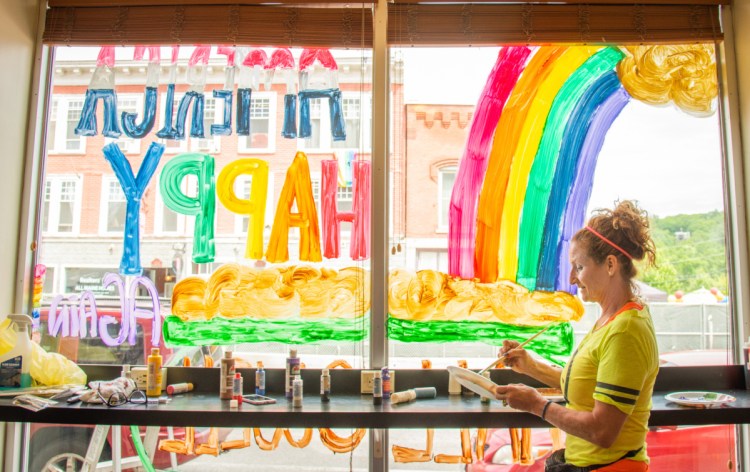 Lynne Violette of Manchester paints the window of Mulligan's in Hallowell on Saturday. The newly opened sandwich shop created the painting in celebration of Hallowell LGBTQ Pride.