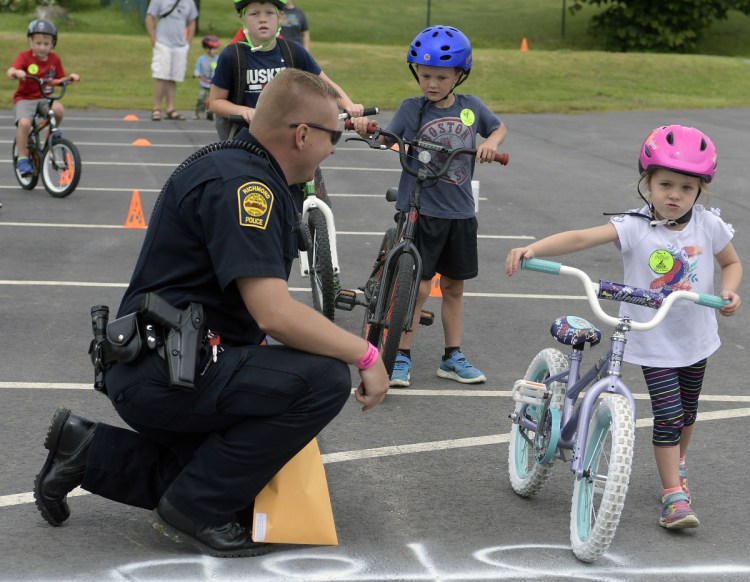 Katie Emmons, 4, walks her bike through a stop sign Sunday under the supervision of Richmond police Officer Will Towle during the annual bicycle rodeo for young riders in the community.
