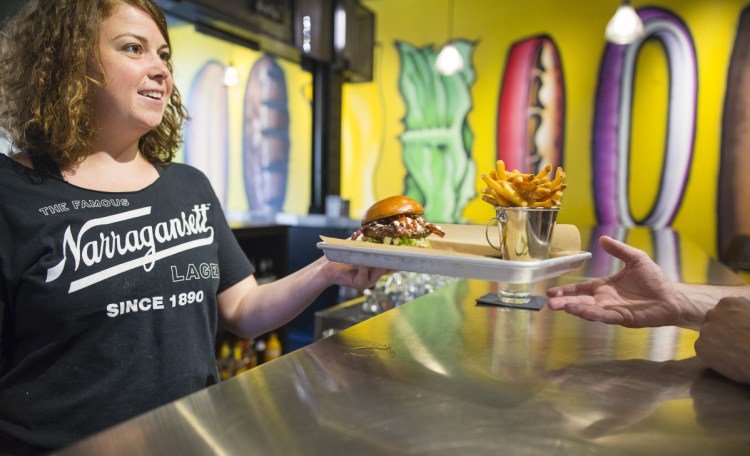 Server Maya Doyle delivers fries and a burger – with bacon, barbecue sauce and feta cheese – to Garrett Jones of Portland on Friday at BRGR Bar on Brown Street in Portland.
