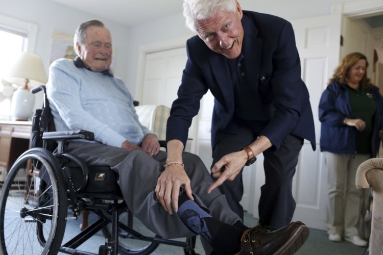 Former Democratic President Bill Clinton jokes with former Republican President George H.W. Bush as Bush shows off a pair of "Bill Clinton socks," while Clinton visits Bush at his home in Kennebunkport on Monday.