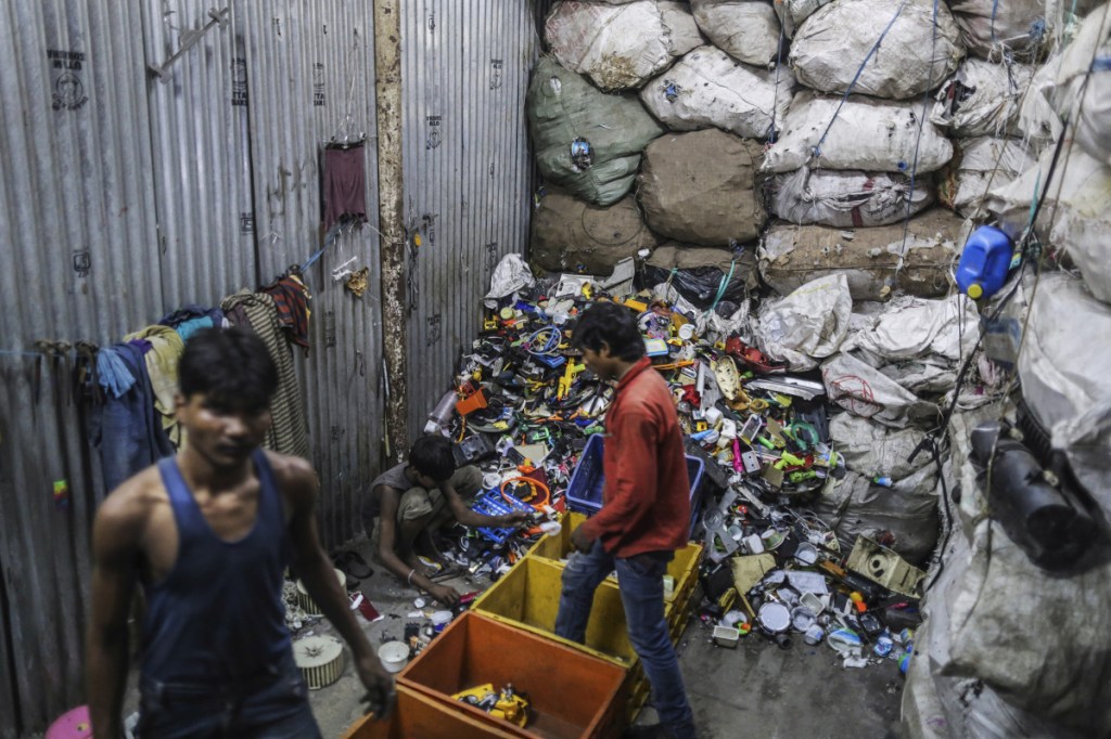 Workers sort through plastic waste for recycling in a slum area of Mumbai, India. The city is criminalizing plastic-bag use with fines – and jail for repeat offenders.