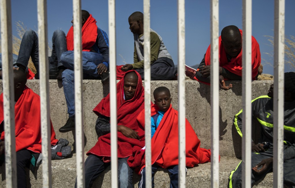 Migrants rest at the port of Algeciras, southern Spain, as they wait to be transported to a police station after being rescued in the Strait of Gibraltar Tuesday.