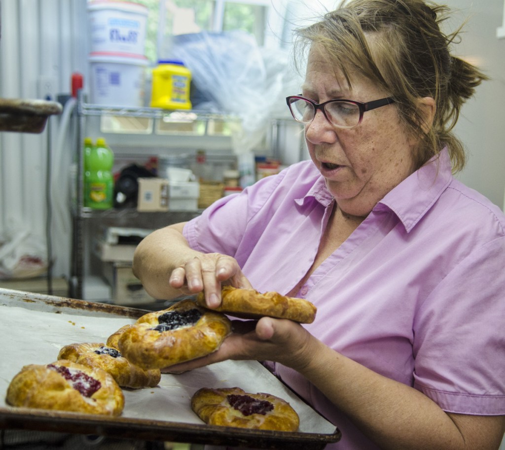 Robin Chase moves Danish pastries from a rack in the back and into the front display case Wednesday at Chase Farm and Bakery in Whitefield.