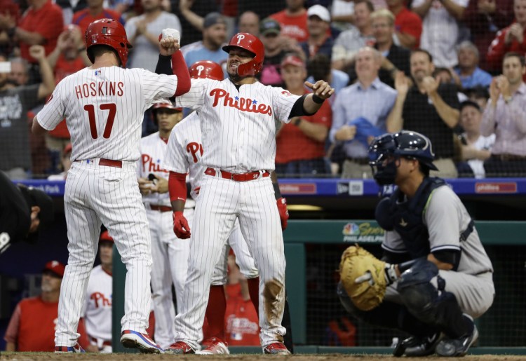 Philadelphia's Rhys Hoskins, left, and Jorge Alfaro, center, celebrate next to New York Yankees catcher Kyle Higashioka after Hoskins hit a three-run homer in the second inning Wednesday night. The Phillies shut out the visiting Yankees, 3-0.