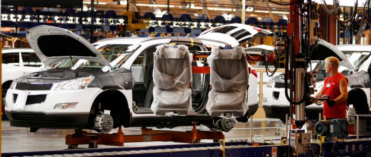Assembly line worker Melvin Matthews uses a large robotic machine to install front seats in a new 2009 Chevrolet Traverse at the GM manufacturing plant in Spring Hill, Tenn.
