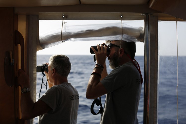 Spanish NGO Proactiva Open Arms captain Riccardo Gatti, right, and volunteer Victor Aguinaga look at the horizon with binoculars in search of migrants in the Mediterranean Sea.